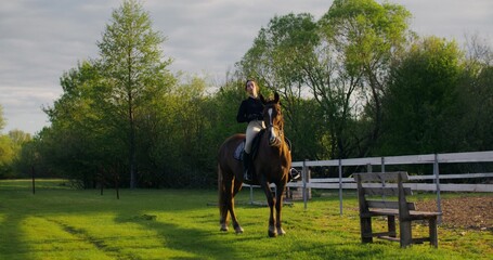 Portrait of a woman on a horse. She poses looking at the camera. Riding a horse on a summer day