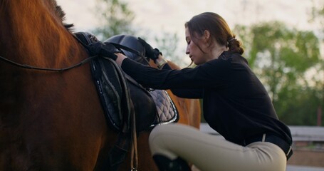 A woman sits in the saddle of a horse and happily looks at the camera
