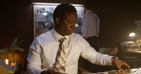 Two detectives are intently examining the evidence. They work in an office