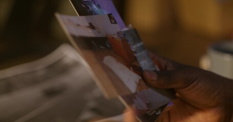 The detective examines photographs from the scene of the attack. Close-up of his hands,...