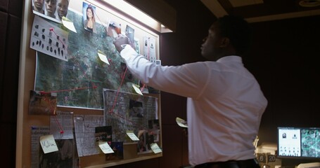 The detective puts sticky notes on a board with photos. Solving a crime