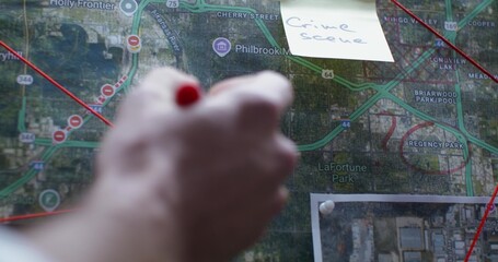 The detective marks a place on the map with a red marker. Close-up of his hand, unrecognizable...