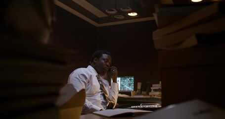 A detective listens to an audio recording on a dictaphone. He works in the office next to his...