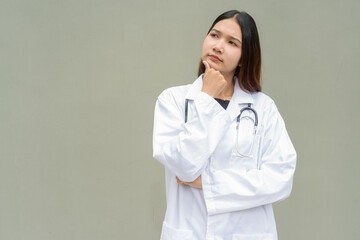 Young Asian woman doctor wearing white lab coat and stethoscope thinking