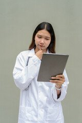 Young Asian woman doctor wearing white lab coat and stethoscope using digital tablet computer