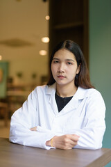 Young woman doctor wearing white lab coat and stethoscope sitting hospital library reception