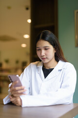 Young woman doctor wearing white lab coat and stethoscope sitting hospital library reception