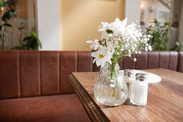 Fresh flowers adorn a cozy cafe table in the afternoon