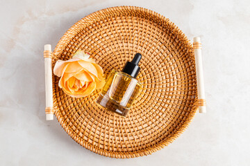 Top view of the glass cosmetic dropper bottle with natural self-care lies on a round wicker tray. natural cosmetics. A blank bottle mockup.