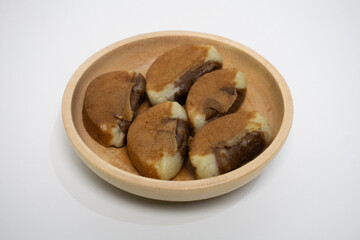 Five golden brown Banyumas pukis cakes in a wooden bowl.