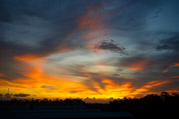 Obraz premium Orange sunlight reflects off the calm ocean as the sun sets over the horizon, painting the sky with beautiful clouds