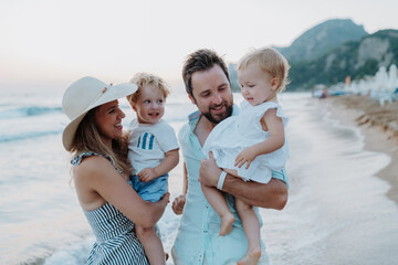 Parents with small children enjoying summer evening by the sea