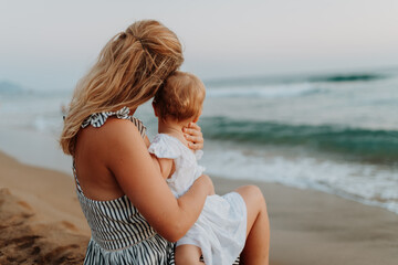 Tender moment between young mom and daughter on sunny beach vacation