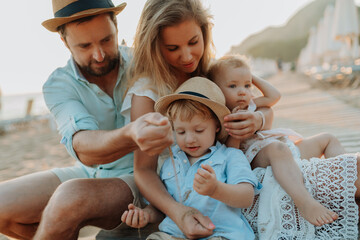 Parents with small children enjoying summer evening by the sea