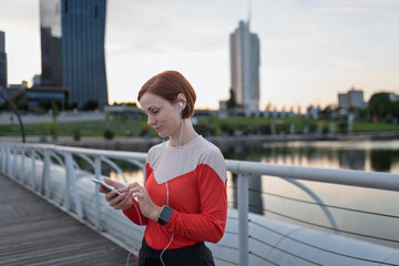 Runner checking her performance on a smartphone during her morning run across a city bridge.