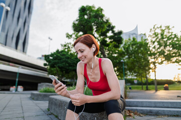 Runner playing music on a smartphone during her morning run across a city bridge.
