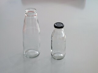 Close-up photo of a two empty reusable glass bottles on a modern grey kitchen table 