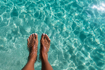 close up top view of womans feet dipping into turquoise water, detailed ripples and light reflections, 