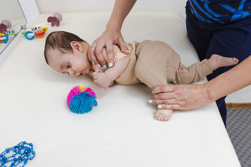 Physical therapist assists child with rollover by correcting leg movement during therapy session....