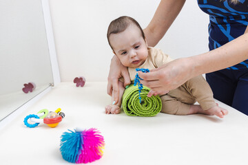 Therapist helps child maintain head position by placing arm on support roll during session. Posture...