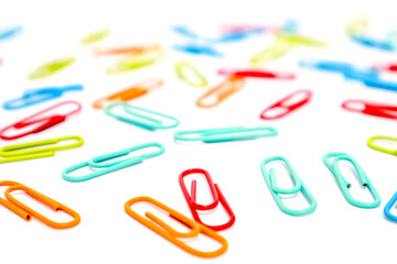 Scattered colorful paper clips on a white surface creating a vibrant pattern and a sense of disorganization or creativity