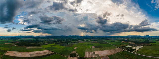 Panorama aerial view of tropical farmland and dramatic storm clouds in evening light