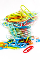 Vibrant Multi-Colored Paper Clips Overflowing from a Container on a White Background