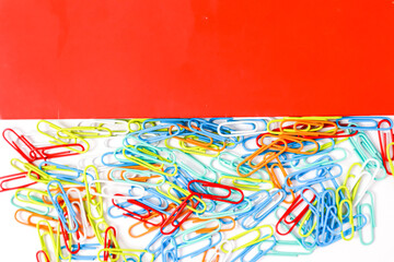 Vibrant and Organized: A Colorful Collection of Paper Clips Against a Red Background
