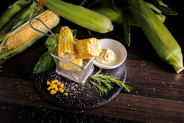 A deliciously boiled corn on the cob served in a restaurant style on a dark background. The vibrant...
