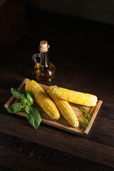 A deliciously boiled corn on the cob served in a restaurant style on a dark background. The vibrant...