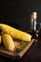 A deliciously boiled corn on the cob served in a restaurant style on a dark background. The vibrant...