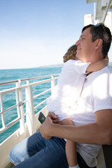 A man and a boy on a white boat in the sea are sitting by the side, father and son are enjoying a sea trip