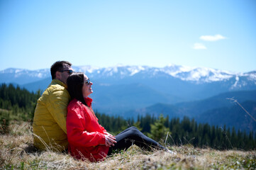Two hikers taking a break on a mountain ridge. Sporty couple with hiking backpacks standing on...