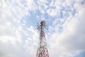 Red and white high-voltage transmission tower in Japan against a cloudy sky.