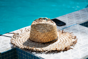 Sun hat and smartphone at the edge of a swimming pool in Tortuguero, Costa Rica, suggesting relaxing vacation