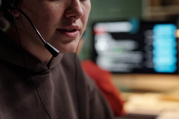 Young adult Caucasian woman wearing headset speaking into microphone, partial face visible, working...