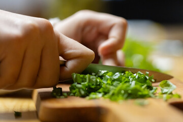 Close-Up of Hands Chopping Fresh Herbs on a Wooden Cutting Board