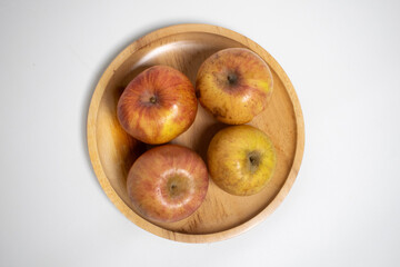 Four apples on a wooden plate