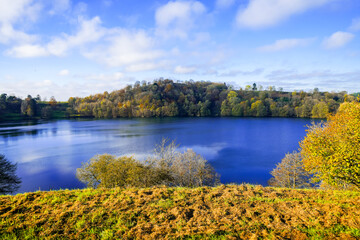 View of the Weinfelder Maar and the surrounding landscape. Nature in the Eifel region in autumn. Totenmaar near Daun.
