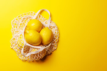 Fresh juicy lemons in a mesh bag, flat lay style
