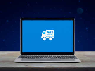 Free delivery truck flat icon on modern laptop computer screen on wooden table over fantasy night sky and moon, Business transportation online concept