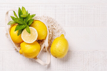 Fresh juicy lemons in a mesh bag, flat lay style