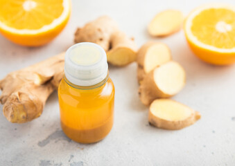 Turmeric energy shot immune drink with ginger root and ripe oranges on light background.Macro.