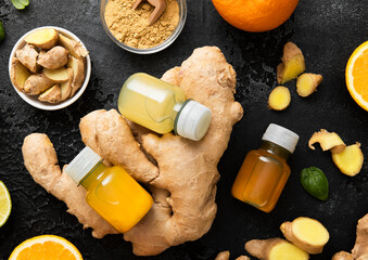 Bottles of immune ginger and orange energy shot drink with ginger root and turmeric powder on black...