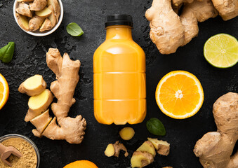 Immune ginger and orange energy shot drink with ginger root and turmeric powder on black kitchen...