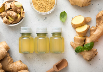 Immune ginger energy shot drink bottles with fresh raw ginger root and powder on light background.Top view.