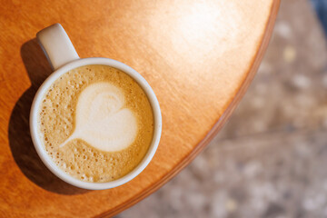 Warm cappuccino in a cup with heart-shaped latte art on top