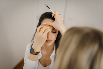 Makeup artist applying foundation on model's face with sponge