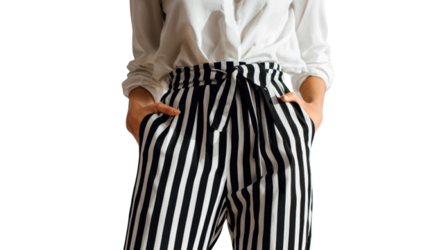 Woman wearing stylish striped trousers and a white blouse, posed hands in pockets, isolated on white background.