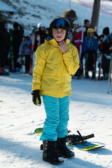 Bright yellow ski jacket stands out against snowy mountain backdrop as young skier prepares for the...